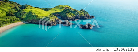 Stunning aerial perspective captures the beauty of a pristine coastline, showcasing vivid turquoise waters gently embracing rocky outcrops and a secluded beach nestled amidst lush green vegetation 133668138