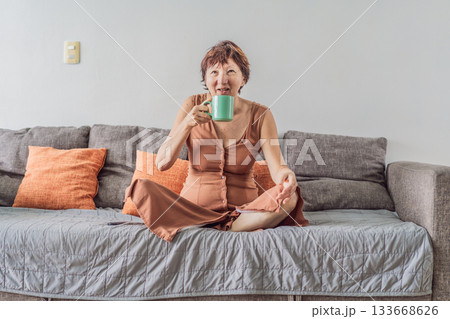 Unaltered senior woman relaxing at home and watching a comedy on TV, enjoying a cozy evening in her living room. Concept of leisure, comfort, positive emotions, mental wellbeing and everyday lifestyle 133668626
