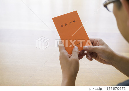 年金手帳を見つめる男性 年金手帳を見つめる男性 133670471