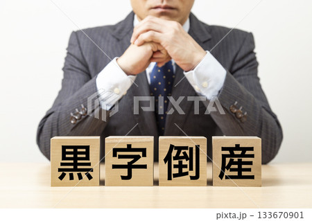 「黒字倒産」と書かれたブロックとビジネスマン 「黒字倒産」と書かれたブロックとビジネスマン 133670901