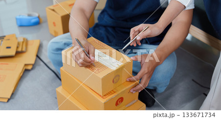 Teamwork in logistics. Two workers labeling boxes in a warehouse. Teamwork in logistics. Two workers labeling boxes in a warehouse. 133671734