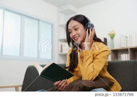 Lifestyle. Young woman enjoying a book while listening to music, embracing relaxation. Lifestyle. Young woman enjoying a book while listening to music, embracing relaxation. 133671766