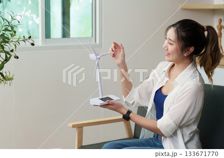 Renewable energy. Woman showcasing a miniature wind turbine model. 133671770