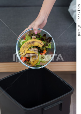 Sustainable living. Woman discarding food waste into trash bin. Sustainable living. Woman discarding food waste into trash bin. 133671789