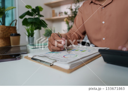 Financial Review. Individual analyzing data charts in a stylish workspace. 133671863