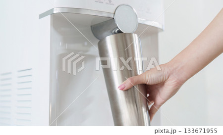 Sustainability. Hand filling stainless steel bottle at water dispenser. 133671955