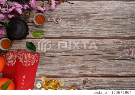 Chinese New Year celebration with tea, oranges, and red envelopes on wooden table 133671964