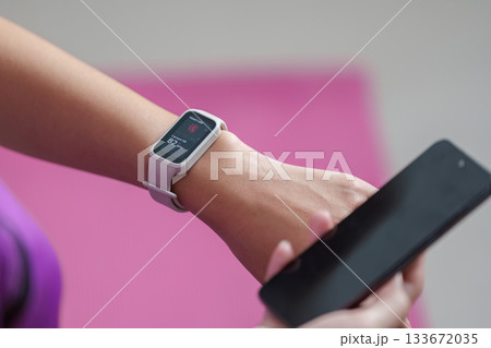 Fitness Tracker. Woman checking heart rate on smartwatch while holding smartphone. Fitness Tracker. Woman checking heart rate on smartwatch while holding smartphone. 133672035