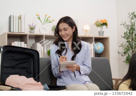 Travel Planning. Woman writing packing list while preparing suitcase. 133672042