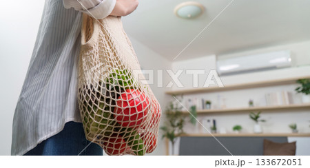 Sustainable living. Woman carrying eco-friendly grocery bag filled with fresh produce. Sustainable living. Woman carrying eco-friendly grocery bag filled with fresh produce. 133672051