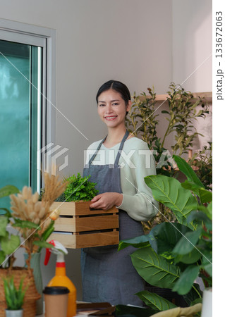 Floral Business. Woman smiling while holding a wooden crate of plants. 133672063