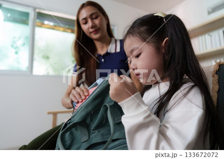 Mother Helping Daughter with Backpack. A caring mother assists her daughter with school supplies. Mother Helping Daughter with Backpack. A caring mother assists her daughter with school supplies. 133672072