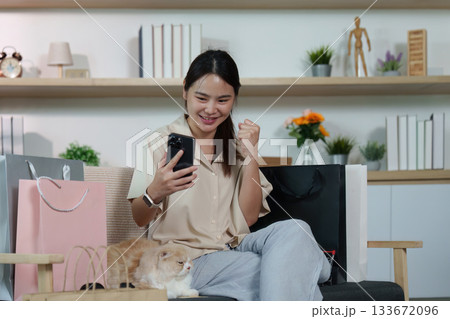 Joyful Shopping. Woman celebrating successful online purchase with smartphone. 133672096