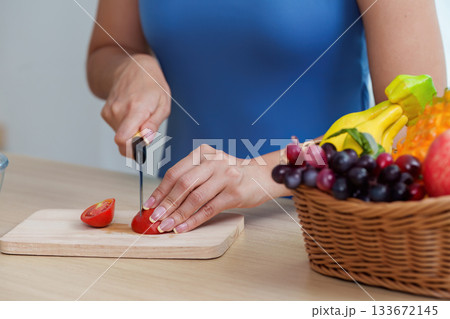 Food Wellness: Woman Cutting Tomato for Nutritious Meal Prep 133672145