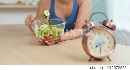 Food Wellness: Woman preparing fresh salad with clock in view Food Wellness: Woman preparing fresh salad with clock in view 133672222