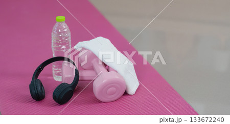 Wellness. Fitness gear including dumbbells, water bottle, and headphones for an active routine. Wellness. Fitness gear including dumbbells, water bottle, and headphones for an active routine. 133672240