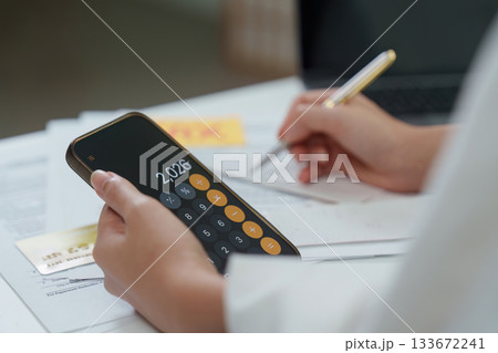 Tax calculation. Individual writing notes while using a smartphone calculator. Tax calculation. Individual writing notes while using a smartphone calculator. 133672241