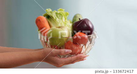 Wellness. Woman holding a bowl of fresh produce, promoting healthy eating habits. Wellness. Woman holding a bowl of fresh produce, promoting healthy eating habits. 133672417