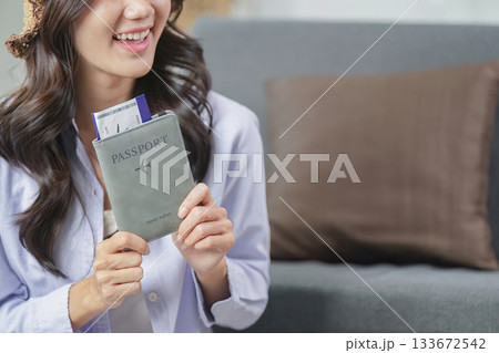 Travel Planning. A woman smiling while holding her passport and travel documents. 133672542