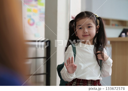 Playful Farewell. Young girl waving at mother before school. 133672578