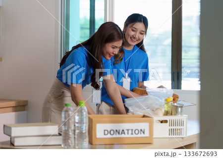 Volunteering for Food Donation. Two young women organizing donations in a community center. 133672693