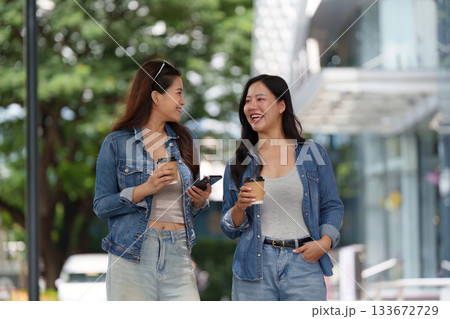 Friendship and Connection. Two young women enjoying coffee and conversation outdoors. Friendship and Connection. Two young women enjoying coffee and conversation outdoors. 133672729