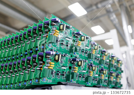 Rows of assembled green printed circuit boards with power electronics components in modern automated manufacturing plant Rows of assembled green printed circuit boards with power electronics components in modern automated manufacturing plant 133672735