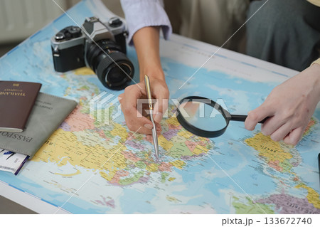 Travel Planning. Two friends exploring destinations on a map with camera and passport. 133672740