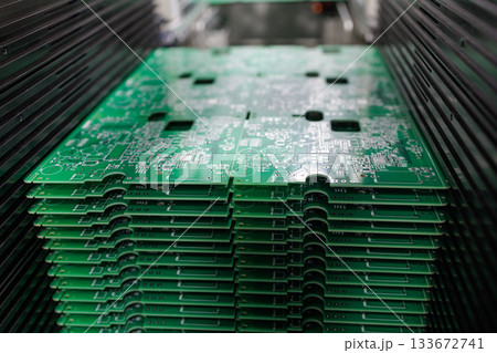 Closeup view of stack of green printed circuit boards in modern electronics manufacturing plant concept of technology industry production Closeup view of stack of green printed circuit boards in modern electronics manufacturing plant concept of technology industry production 133672741