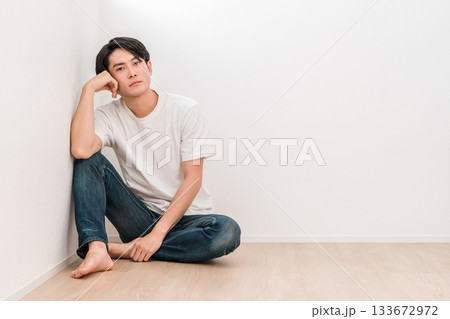 白い壁のリビングに座るジーンズ姿の若いアジア人男性 133672972