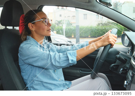 Woman driving small car, focusing on road ahead Woman driving small car, focusing on road ahead 133673095