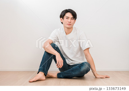 白い壁のリビングに座るジーンズ姿の若いアジア人男性 白い壁のリビングに座るジーンズ姿の若いアジア人男性 133673149