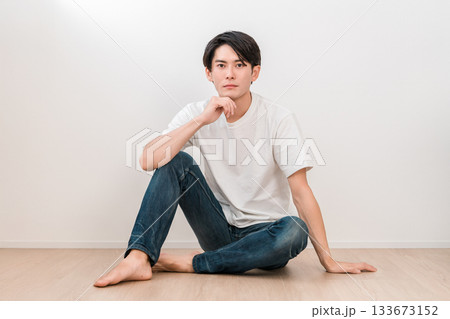白い壁のリビングに座るジーンズ姿の若いアジア人男性 133673152