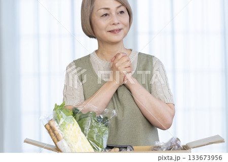 リビングで産地直葬の宅配野菜を喜ぶシニア女性 リビングで産地直葬の宅配野菜を喜ぶシニア女性 133673956
