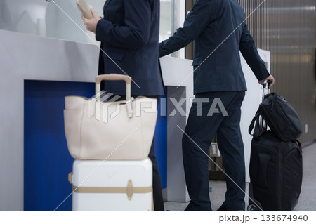 駅や空港などの券売機でチケットを買う出張のビジネス女性　キャリケースや荷物を預ける窓口など　顔無し 133674940