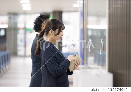 駅や空港などの券売機でチケットを買う出張のビジネス女性 駅や空港などの券売機でチケットを買う出張のビジネス女性 133674942