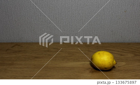 A vibrant lemon placed on a rustic wooden surface. 133675897
