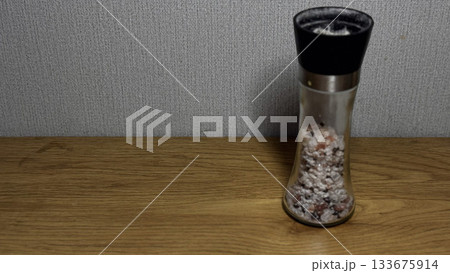 Stylish salt grinder with pink Himalayan salt on wood. 133675914