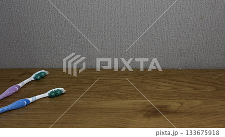 Two vibrant toothbrushes on a wooden table, perfect for dental hygiene themes. Two vibrant toothbrushes on a wooden table, perfect for dental hygiene themes. 133675918
