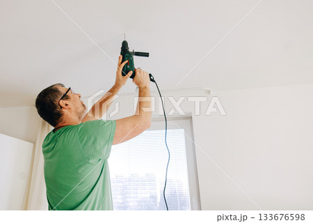 Man using electric drill to 133676598