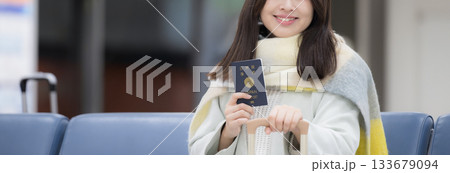 年末年始の海外旅行にいくパスポートを持つ冬服の若い女性　顔無しのバナー 133679094