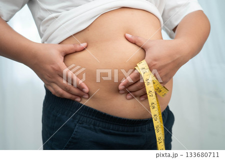 Asian woman use hand to squeeze fat belly big size overweight and obesity. 133680711