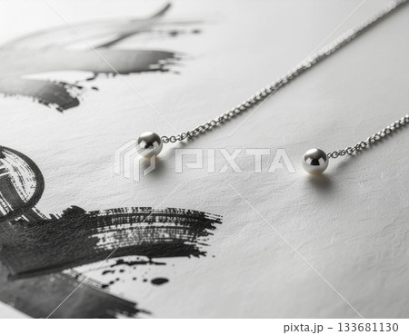 手漉き和紙に滲む墨跡とシルバーアクセサリーの対比──高級感と静寂を兼ね備えた洗練ジュエリー構図 133681130