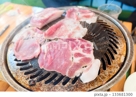 ジンギスカン鍋で焼き始めた豚肉スライス（アウトドア調理） 133681300