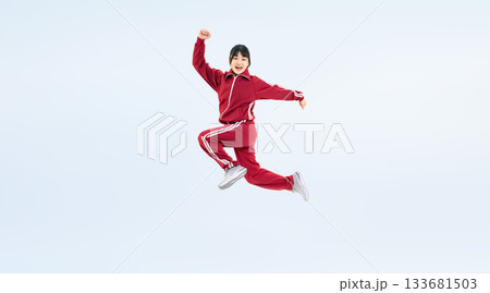 元気にジャンプする体育ジャージを着た女子学生の全身写真 133681503