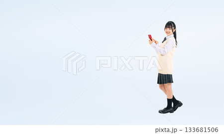 スマホを使う制服を着た女子学生の全身写真 133681506