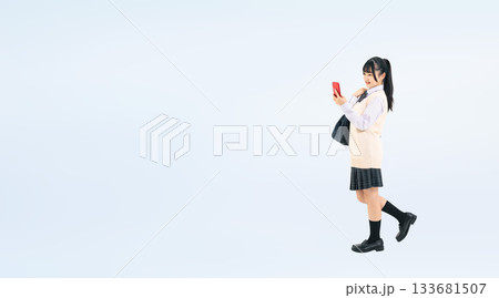 スマホを見ながら歩く制服を着た女子学生の全身写真 スマホを見ながら歩く制服を着た女子学生の全身写真 133681507