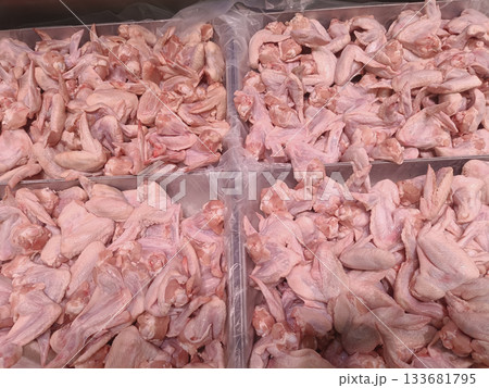 Raw chicken wing pieces piled in market trays with pale pink skin and natural texture, fresh looking and ready for cooking Raw chicken wing pieces piled in market trays with pale pink skin and natural texture, fresh looking and ready for cooking 133681795