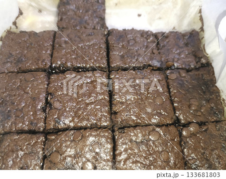 Chocolate brownie squares with glossy chocolate chips and moist texture arranged in baking tray, warm and indulgent Chocolate brownie squares with glossy chocolate chips and moist texture arranged in baking tray, warm and indulgent 133681803