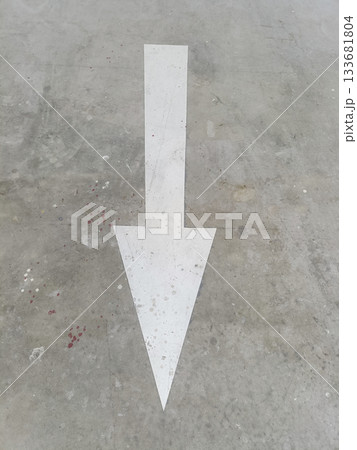 White directional arrow painted on concrete floor pointing forward, minimal urban graphic with worn texture White directional arrow painted on concrete floor pointing forward, minimal urban graphic with worn texture 133681804